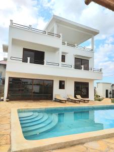 a villa with a swimming pool in front of a house at Luxury White Villa in Nungwi