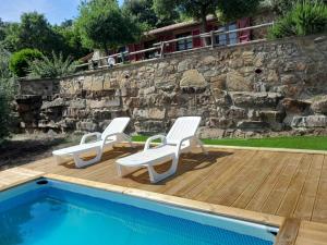 dos sillas blancas sentadas en una terraza junto a una piscina en Casa di campagna in collina, en Tatti