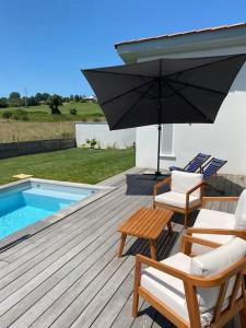 a deck with chairs and an umbrella and a pool at Maison à louer au pays basque in Anglet