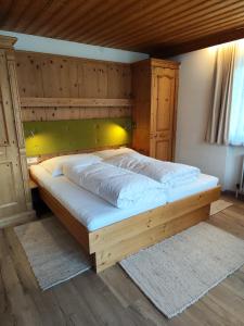 a large wooden bed in a bedroom with a wooden ceiling at Apartmenthaus Bader in Leutasch