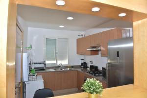 Golf Royal appartement في فاس: مطبخ مع دواليب خشبية وثلاجة حديد قابلة للصدأ