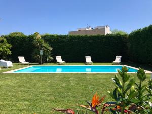 a swimming pool with two lawn chairs and a hedge at Casa Pedro e Inês in Viana do Castelo