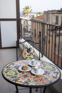 uma mesa com duas chávenas e pratos de comida numa varanda em Appartamento al Mare Sant’Agata em Messina