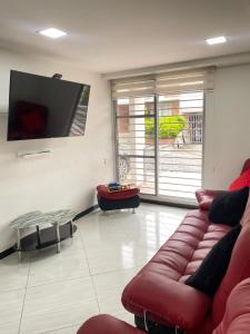 sala de estar con sofá rojo y TV de pantalla plana en casa vacacional en Anapoima, en Anapoima