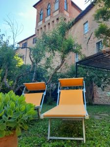 dos sillas sentadas en el césped frente a un edificio en "Il Pollaio" guests house, en Panicale
