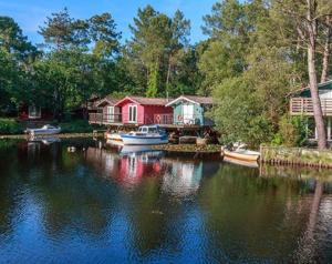 a house on a river with boats in the water at Appartement à 2 pas océan et lac in Lacanau