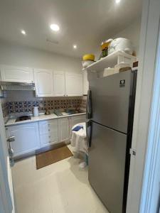 a kitchen with white cabinets and a stainless steel refrigerator at Appartement Sur La Plage in Hammamet