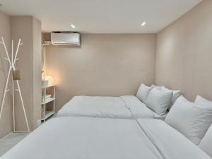 1 dormitorio con 2 camas y almohadas blancas en Hoho House en Busan