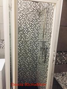 a shower in a bathroom with black and white tiles at Domus KA 2 in Cremona