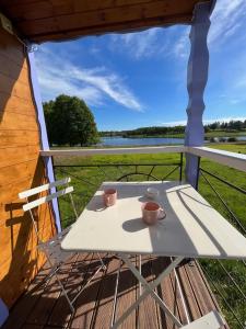 a table on a porch with two cups on it at Les logements insolites de la Base Nautique in Verneuil