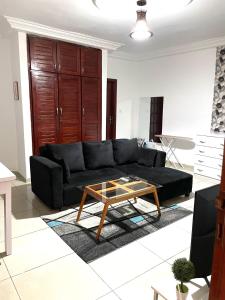Sala de estar con sofá negro y mesa de centro en Cheb's House, en Abiyán