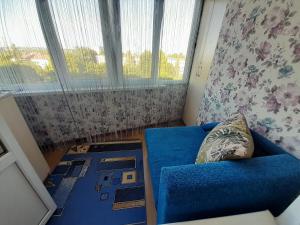 Habitación pequeña con sofá azul y ventana en Апартаменти біля Автовокзалу, en Rivne