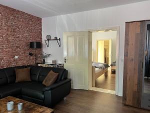 uma sala de estar com um sofá preto e uma parede de tijolos em Ferienwohnung Nauen Familie Renner em Nauen