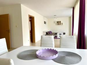 Rusalka Apart-Residence في ابزور: طاولة بيضاء مع وعاء أرجواني فوقها
