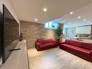 un soggiorno con divano rosso e muro di mattoni di R39 Elegant Apartment with Private Parking a Milano