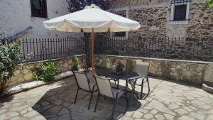 a table and chairs with an umbrella on a patio at The Stone House in Halkidiki in Vávdhos