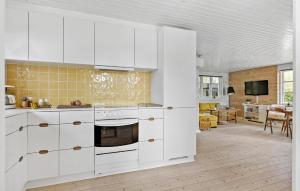 a kitchen with white cabinets and a living room at 3 Bedroom Awesome Home In Brenderup Fyn in Skovs-Højrup