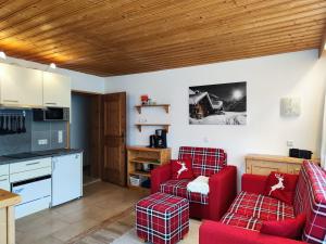 a living room with two red chairs and a kitchen at Apartments Bader Leutasch Tirol in Leutasch