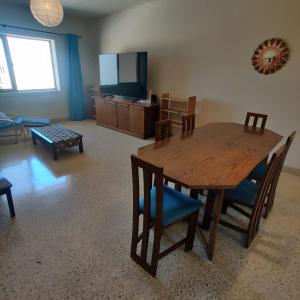 a living room with a wooden table and chairs and a television at SeaView Apartment in Taʼ Ġokondu