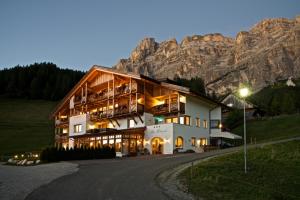 a large building with a mountain in the background at Hotel Ciasa Rü Blanch in San Cassiano