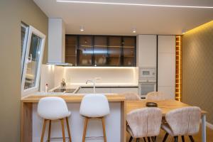 a kitchen with a wooden table and white chairs at Vila Klaro in Shkodër