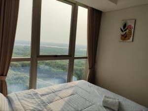 a bed in a room with a large window at Apartment gold coast Pik in Jakarta