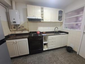cocina con armarios blancos y fogones negros en Plaza 23, en Bahía Blanca 10 fotos más