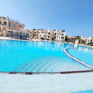 a large blue swimming pool with buildings in the background at Chalet 3 bedrooms 2 toilets lotus north cost stand alone 3 air conditioner families are preferred available all year days & 3 blankets available in El Alamein