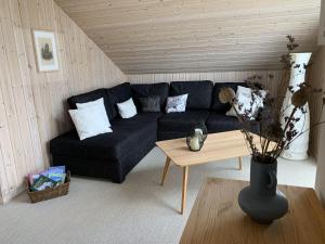 ein Wohnzimmer mit einem schwarzen Sofa und einem Tisch in der Unterkunft Holiday home Seeidyll am D mmer See D mmer in Dümmer
