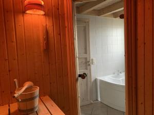 ein Badezimmer mit einer Badewanne, einem Waschbecken und einem Eimer in der Unterkunft Holiday home Seeidyll am D mmer See D mmer in Dümmer