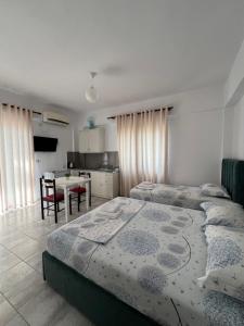 a bedroom with two beds and a table and a kitchen at Dea Apartament in Ksamil