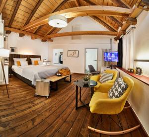 a bedroom with a bed and a couch and chairs at Weinforum Franken Hotel & Restaurant in Eibelstadt