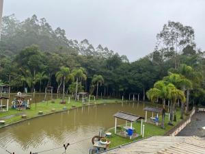 a park with a pond with a playground and trees at Pesqueiro Restaurante e Pousada Pingo de Ouro in Piedade