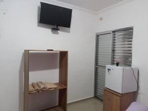 a room with a refrigerator and a tv on the wall at Pesqueiro Restaurante e Pousada Pingo de Ouro in Piedade
