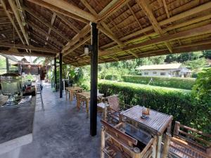 a patio with tables and chairs under a wooden roof at Samui Camping Farm in Laem Sor