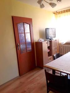 Habitación con puerta, mesa y TV en Apartament *Jasmine* en Dąbrowa Górnicza