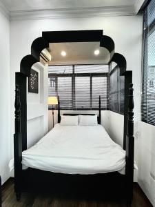 a bedroom with a black bed with white sheets at Indochine Design Apartment Hotel 5 - Hanoi Old Quarter in Hanoi