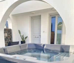 bañera en una habitación con espejo grande en Alafropetra Luxury Suites, en Akrotiri