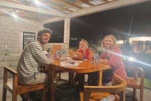 three people sitting at a table with a laptop at Onion Garden And Natural Hotspring in Kubupenlokan