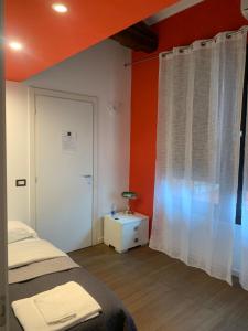 a bedroom with orange walls and a bed and a window at LT - Room's Bed & Living in Monza