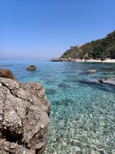 a beach with clear blue water and rocks at Sunny House in Parghelia