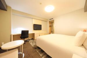 Habitación de hotel con cama, escritorio y TV. en Richmond Hotel Narita, en Narita