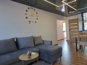 sala de estar con sofá y reloj en la pared en apartament klif, en Gdynia