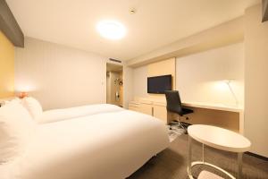 a hotel room with a white bed and a desk at Richmond Hotel Narita in Narita