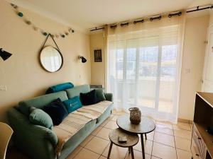 uma sala de estar com um sofá verde e uma mesa em Appartement rez-de-chaussée entre dunes et ocean em Lacanau-Océan