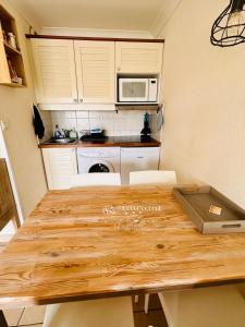 uma cozinha com uma mesa de madeira e um micro-ondas em Appartement rez-de-chaussée entre dunes et ocean em Lacanau-Océan