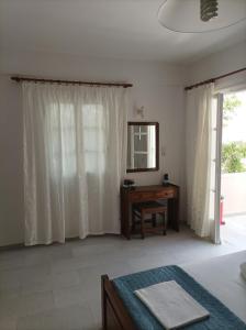 Schlafzimmer mit einem Bett, einem Schreibtisch und einem Spiegel in der Unterkunft Asiminas in Naxos Chora