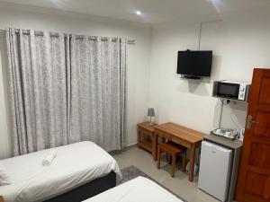 a small room with a bed and a television at Serenity Guest Lodge in Kokstad