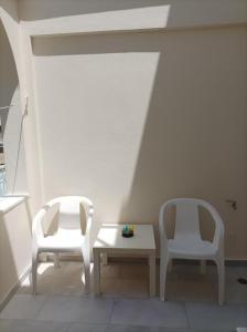 2 weiße Stühle und ein Tisch in einem Zimmer in der Unterkunft Asiminas in Naxos Chora