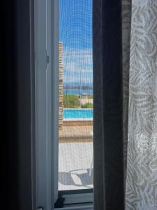 een open raam met uitzicht op een zwembad bij Summer House in Corfu Town in Mantoúkion